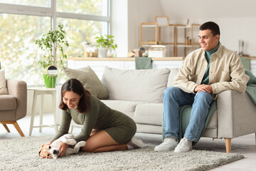 Young couple with cute Beagle dog at home