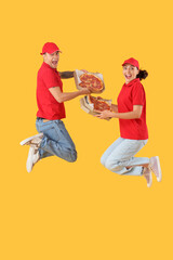 Fototapeta na wymiar Young couriers with tasty pepperoni pizza jumping on yellow background
