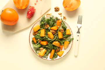 Plate of delicious salad with persimmon and walnut on yellow background