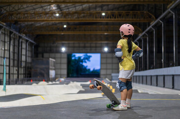 asian child skater or kid girl start riding surf skate at indoor pump track or fun playing skateboard in skate park by extreme sports surfing to wearing helmet elbow pads wrist knee guard body safety © kornnphoto