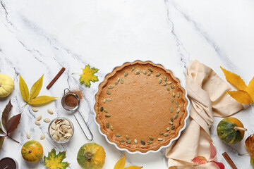 Autumn composition with tasty pumpkin pie on white marble background