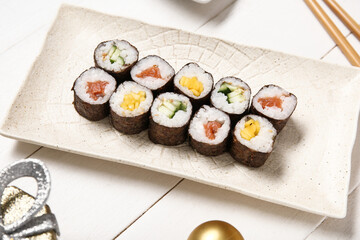 Plate with tasty sushi rolls on white background