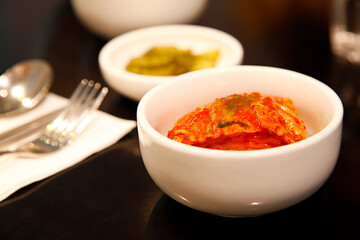 Kimchi served in a white bowl on a wooden table. Selective focus.