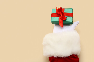 Santa Claus with green gift box on beige background