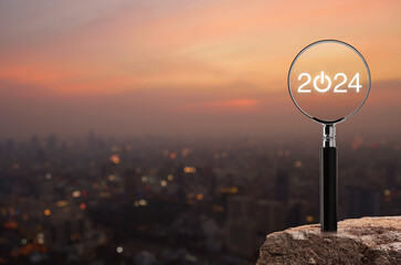 2024 start up flat icon with magnifying glass on rock mountain over blur of cityscape on warm light...