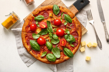 Wooden board of tasty Pepperoni pizza with tomatoes and basil on white background