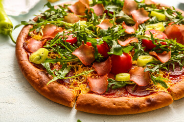 Delicious pizza with tomatoes and arugula on light blue background