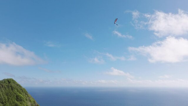 Freedom concept. Epic aerial of extreme sportsman flying paraglide above scenic green Hawaiian mountain. Extreme sport on paradise tropical island Oahu. Cinematic nature landscape 4K. People lifestyle