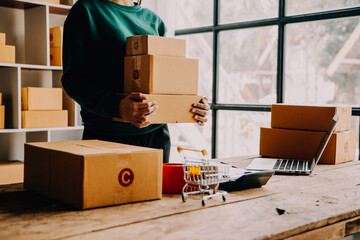 Startup small business entrepreneur or freelance Asian woman using a laptop with box, Young success Asian woman with her hand lift up, online marketing packaging box and delivery, SME concept.
