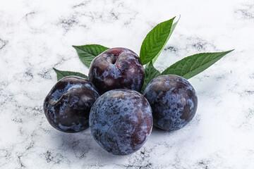 Raw purple plums heap with leaves
