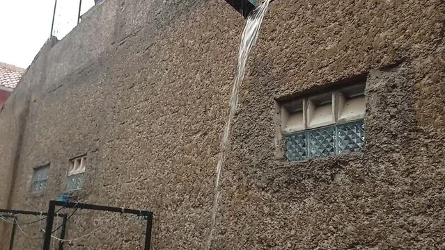 close-up rainwater flows down a drainpipe. Heavy rain in the city.