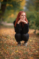 Portrait of a young beautiful red-haired girl in an autumn park.