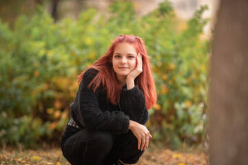 Obraz premium Portrait of a young beautiful red-haired girl in an autumn park.
