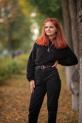 Portrait of a young beautiful red-haired girl in an autumn park.