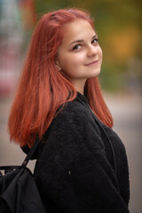 Portrait of a young beautiful red-haired girl in an autumn park.