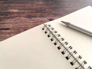 木製テーブルの上で開いたリングノートとボールペン
