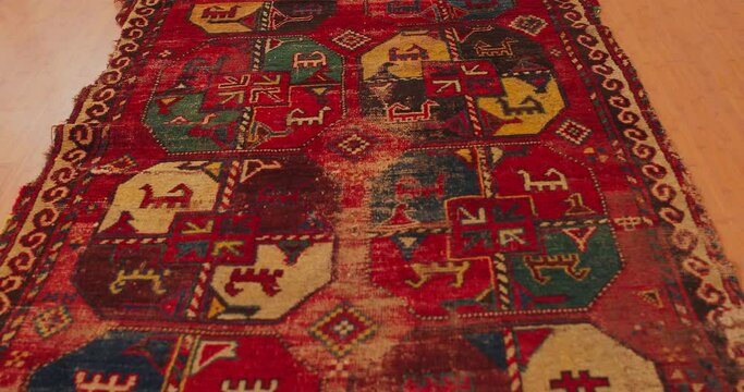 Close up shot of an old shabby handmade carpet made by Samarkand masters using ancient technology. It is covered with national patterns and ornaments. Uzbekistan.