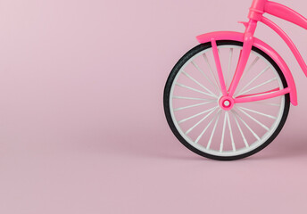 A toy bicycle wheel on a pink background.