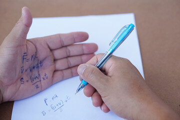 Palm with written physics formula on it during doing writing examination on paper by pen. Concept, cheat the test, Dishonest behaviour. Education assessment.
