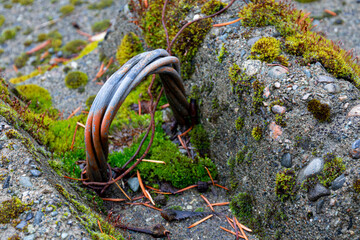 An abstract image of rusted cables imbedded into a concrete barricade and used as a hook. 