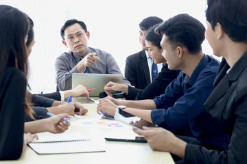 Businesspeople at conference, seriously senior businessman pointing at someone to answer question at group meeting. Elderly boss discussing with teammate, company teamwork brainstorming meeting.