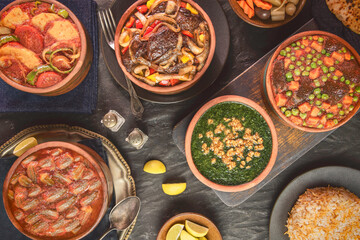 Arabic Cuisine; A variety of Middle Eastern traditional tagines such as potatoes, okra, peas, meat and molokhiya. Served with vermicelli rice and bread. Top view with close up.