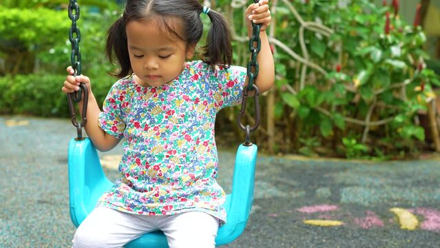 Cute little asian girl enjoying play with swing outdoor city playground child play outdoor activity 