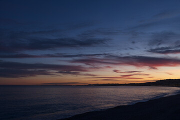 Fototapeta na wymiar Purple sunset on the French Riviera pebble beach in Nice