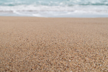 Fototapeta na wymiar Closeup photo of sandy beach with small waves background