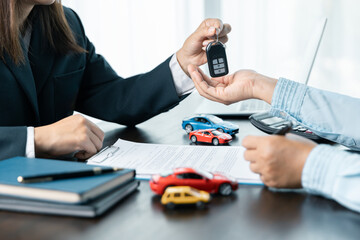 Young woman receives a key from car salesman. After approval agreeing to a contract for rent or sale of a car at workshop, loan car, insurance, sale, buying car and finance concept.
