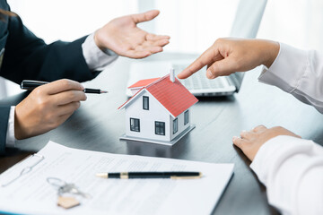Discussion with a real estate agent, House model with agent and customer discussing for the contract to buy, get insurance or loan real estate or property. approved mortgage application form.