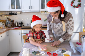 Mom and daughter in the white kitchen are preparing cookies for Christmas and new year. Family day, preparation for the holiday, learn to cook delicious pastries, cut shapes out of dough with molds