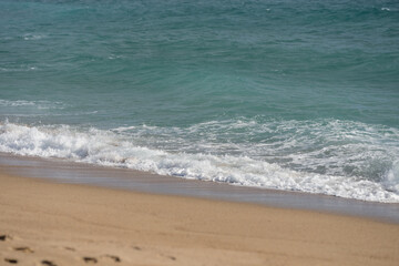 Fototapeta na wymiar Waves rolling on a sandy beach on a sunny day