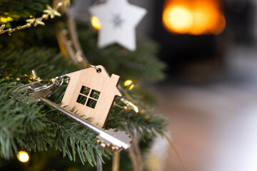 Key to the house with a keychain is hanging on the Christmas tree. A gift for New Year, Christmas....