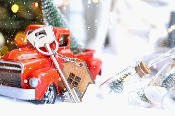 Red retro car with a Christmas tree decorates with the house key in the pickup truck for Christmas. Buying a home, moving, mortgage, loan, real estate, festive mood, New Year