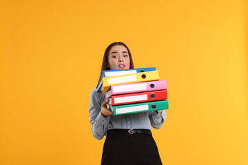 Stressful woman with folders on orange background