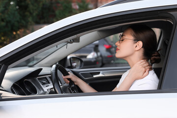 Young woman suffering from neck pain in her car