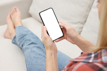 Woman using smartphone on couch at home, closeup. Space for text