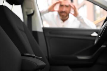 Automobile lockout, key forgotten inside, selective focus. Emotional man looking through car window - obrazy, fototapety, plakaty