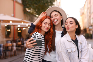 Obraz premium Happy friends taking selfie on city street