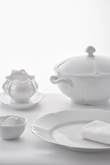 set of white porcelain tableware on a white tablecloth, shallow depth of field