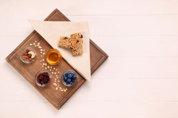 Tasty granola bars served on white wooden table, top view. Space for text