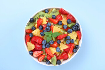 Obraz na płótnie Canvas Yummy fruit salad in bowl on light blue background, top view