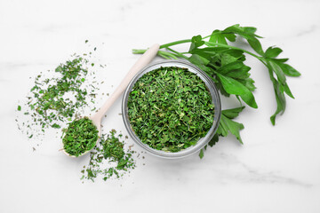 Dried aromatic parsley and fresh leaves on white marble table, flat lay