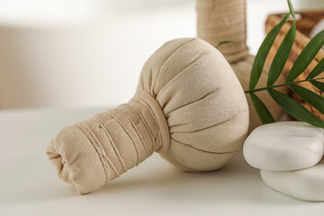 Spa composition. Herbal bags, stones and palm leaves on white table, closeup