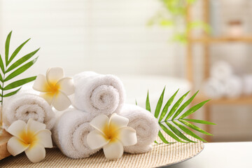 Obraz na płótnie Canvas Spa composition. Towels, plumeria flowers and palm leaves on white table in bathroom
