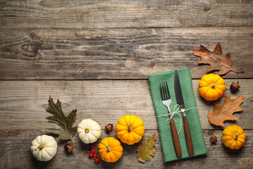 Cutlery, napkin and autumn decoration on wooden background, flat lay with space for text. Table...