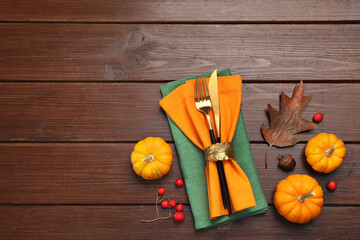 Cutlery, napkins and autumn decoration on wooden background, flat lay with space for text. Table...