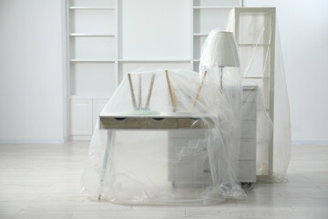 Modern furniture covered with plastic film at home