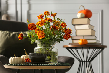 Beautiful autumn flowers, cup of drink and pumpkins on coffee table indoors, space for text